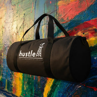 My Store H2Elite heavyweight black cotton canvas duffel bag with white hustle graphic against a colorful wall.